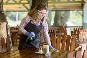 A woman is cleaning a wooden table at a restaurant