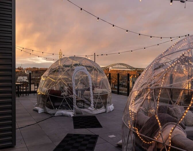 A picture showing an outdoor patio restaurant with an igloo.
