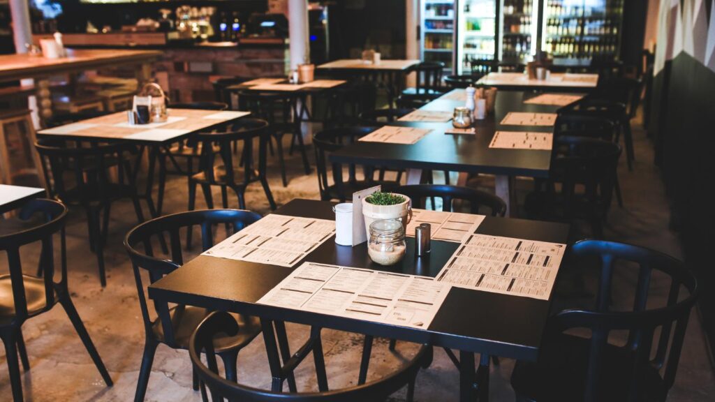 a restaurant with dining room chairs and table with menu on top.